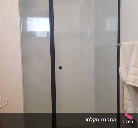 מקלחון חזית זכוכית שקופה עם מסגרת וצירים שחורים מותקן בנישה
